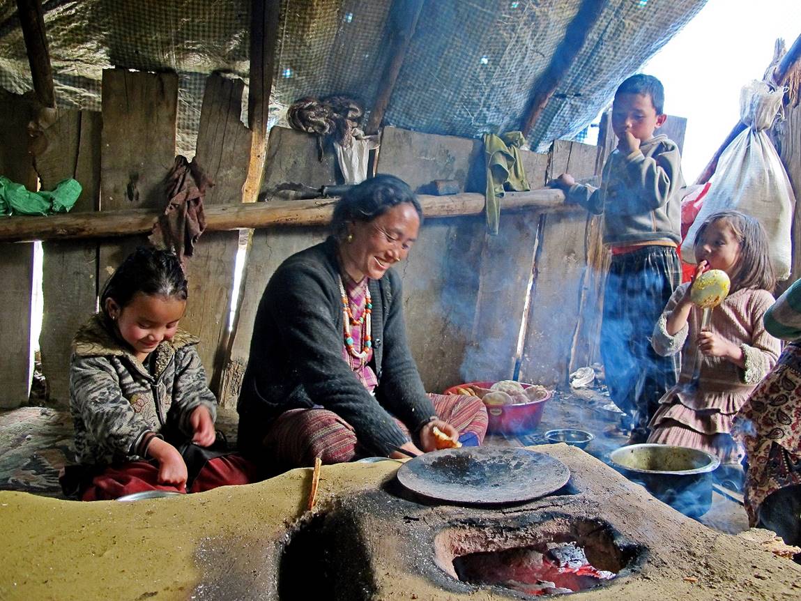 A person and children cooking in a hut

Description automatically generated
