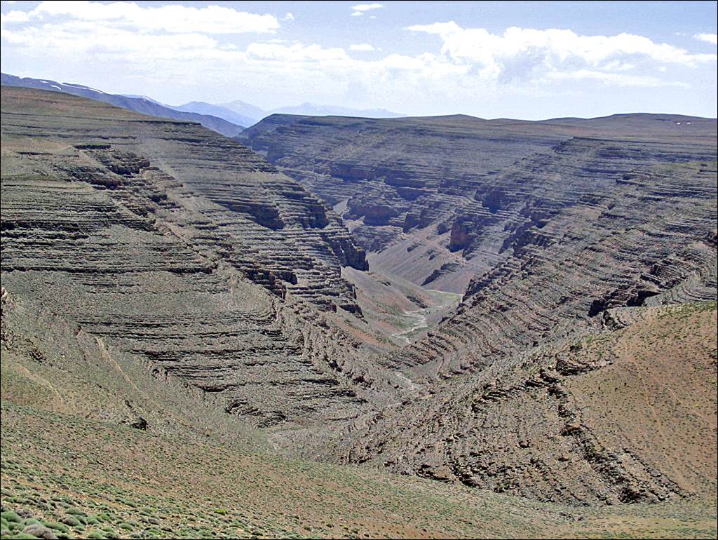 A large canyon with a valley in the background

Description automatically generated