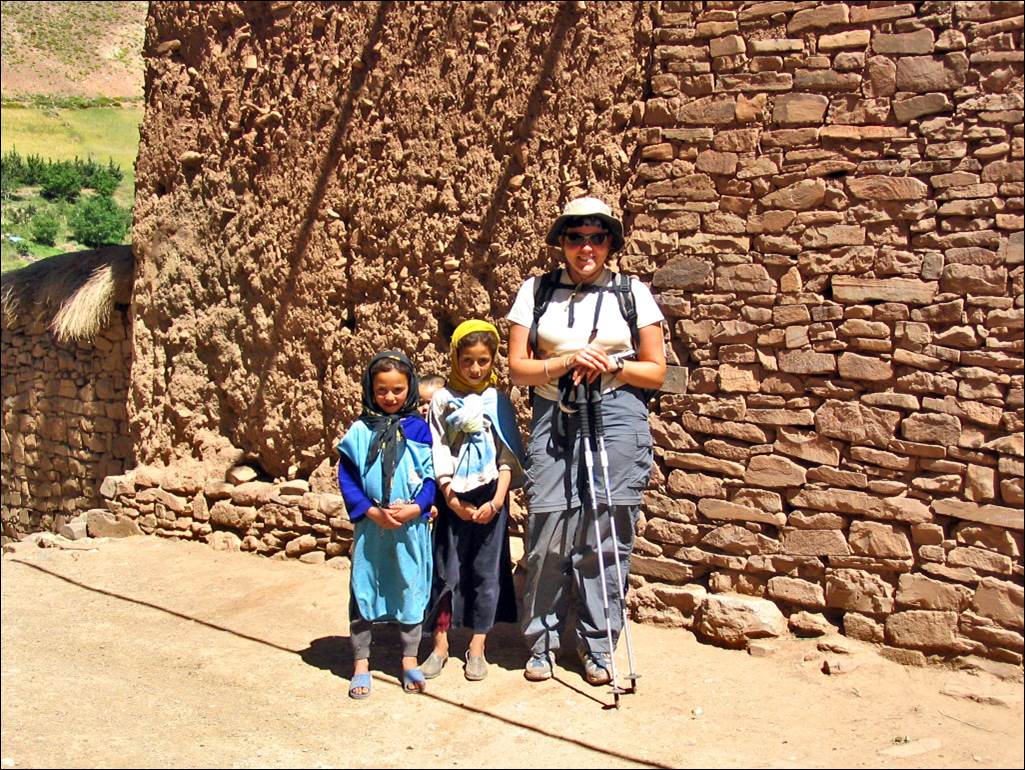A person and two children standing in front of a stone wall

Description automatically generated