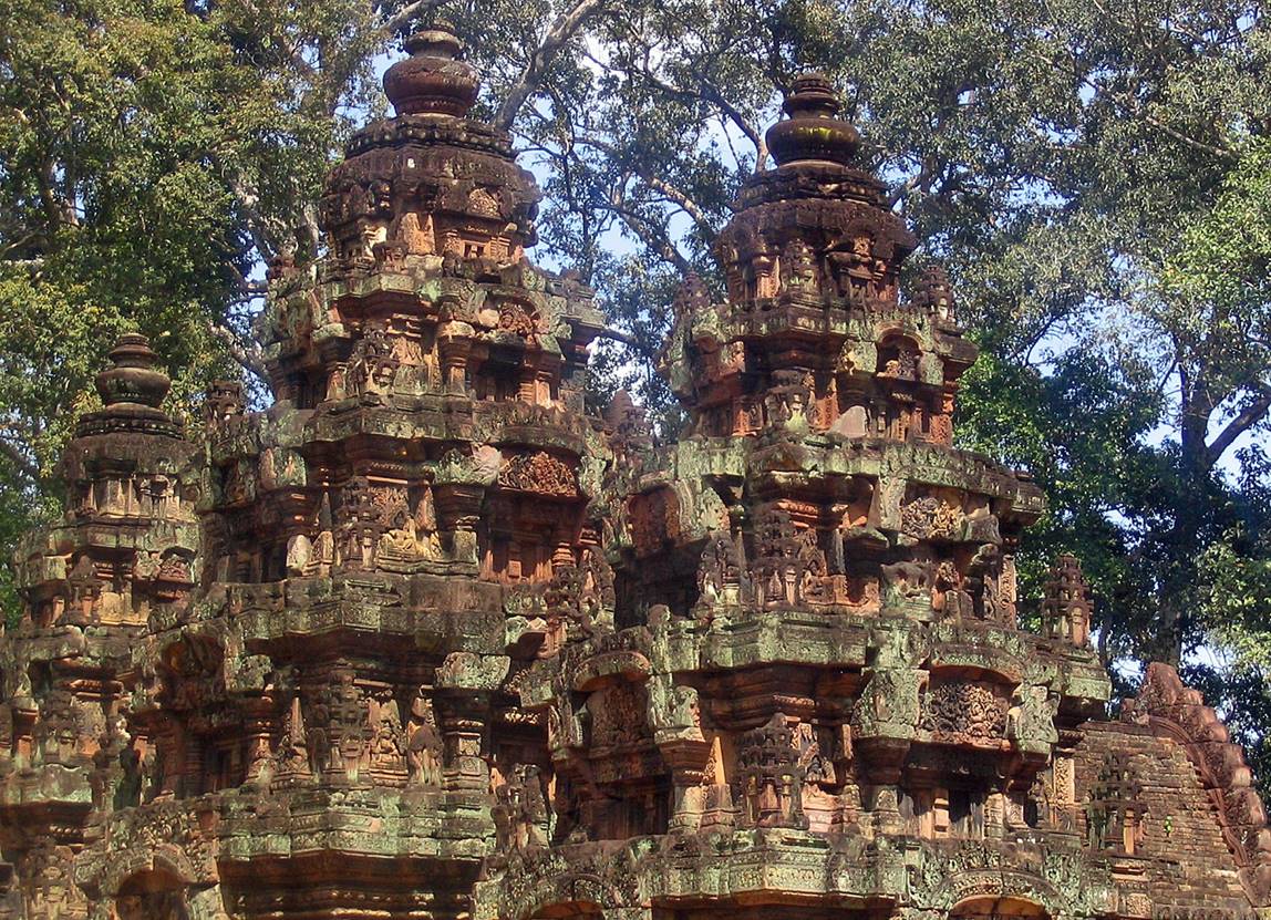 A stone structure with many carvings with Banteay Srei in the background

Description automatically generated with medium confidence