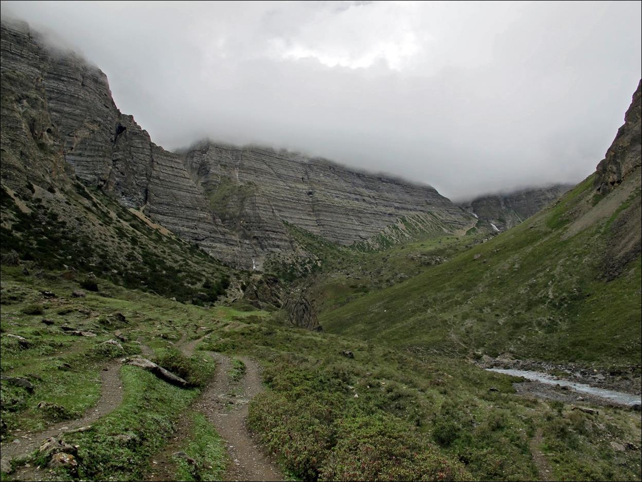 A trail in a valley with mountains in the background

Description automatically generated