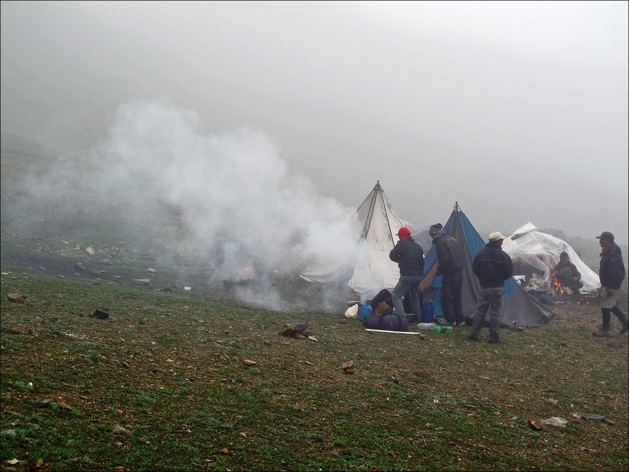 People standing in a field with tents and smoke

Description automatically generated