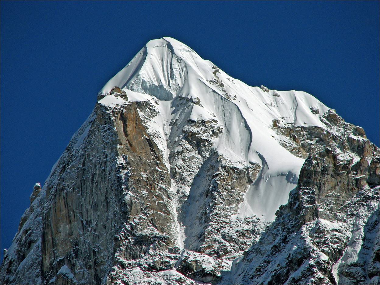 A snowy mountain peak with blue sky

Description automatically generated