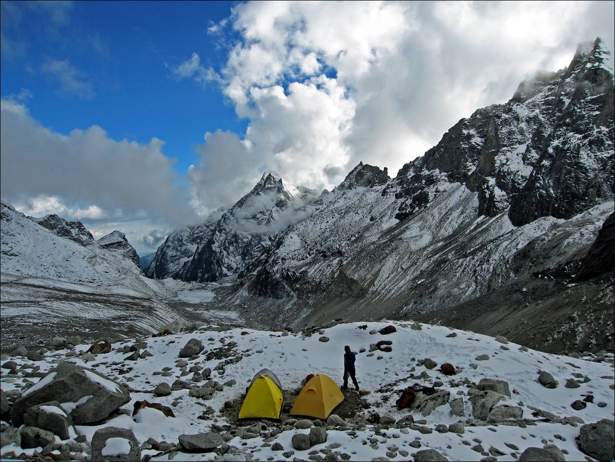 A person standing next to a group of tents in a snowy mountain

Description automatically generated