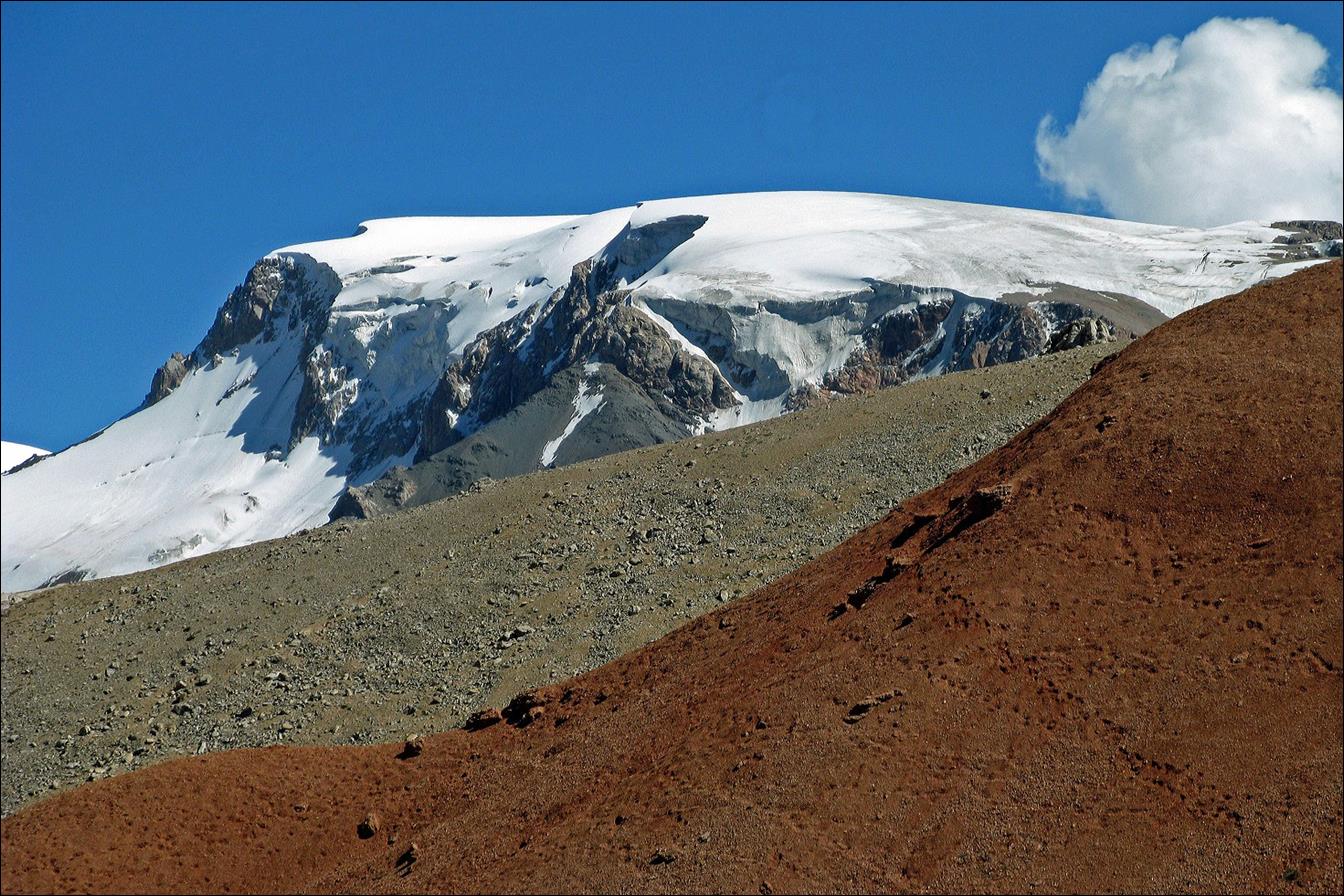 A snow covered mountain and a red hill

Description automatically generated with medium confidence