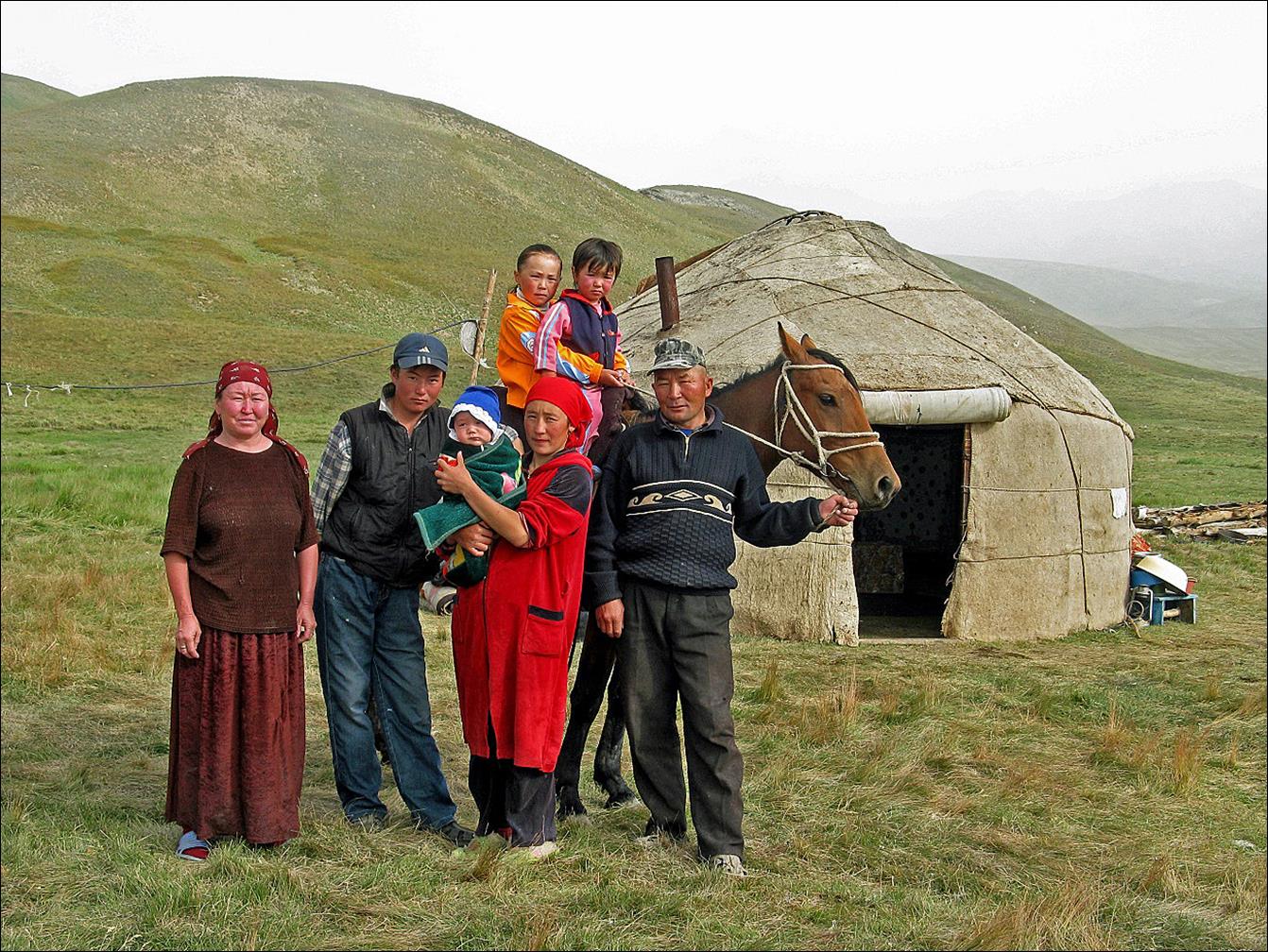 A group of people standing in front of a small hut

Description automatically generated
