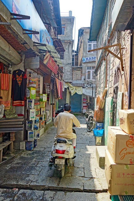 A person riding a scooter through a narrow alley

Description automatically generated with medium confidence